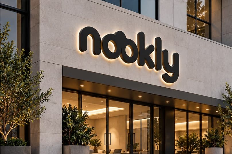 Taş bir bina cephesinde ışıklı Nookly logosu